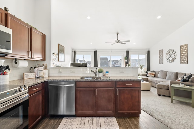 kitchen with a sink, a peninsula, backsplash, and stainless steel appliances