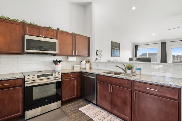 kitchen featuring light stone countertops, backsplash, appliances with stainless steel finishes, and dark wood-style flooring