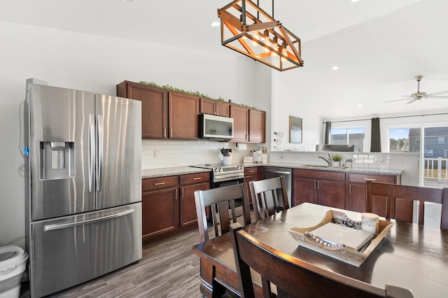 kitchen with dark wood-style flooring, backsplash, appliances with stainless steel finishes, and a sink