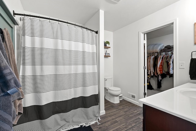 full bath with visible vents, a walk in closet, toilet, wood finished floors, and vanity