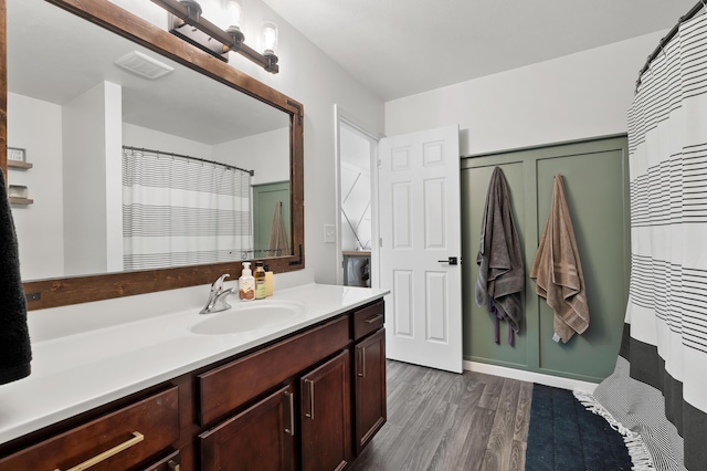 full bathroom with visible vents, vanity, a shower with shower curtain, and wood finished floors