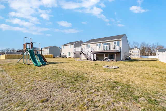 back of property with a yard, a deck, stairs, and a playground