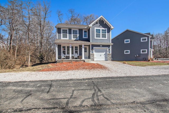 view of front of house featuring board and batten siding, gravel driveway, a porch, stone siding, and an attached garage