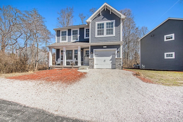 traditional home featuring board and batten siding, gravel driveway, a porch, stone siding, and an attached garage