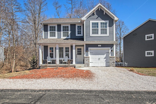 traditional-style home featuring driveway, stone siding, covered porch, board and batten siding, and a garage