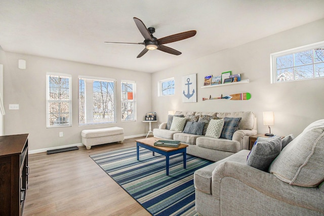 living area with baseboards, a healthy amount of sunlight, and wood finished floors