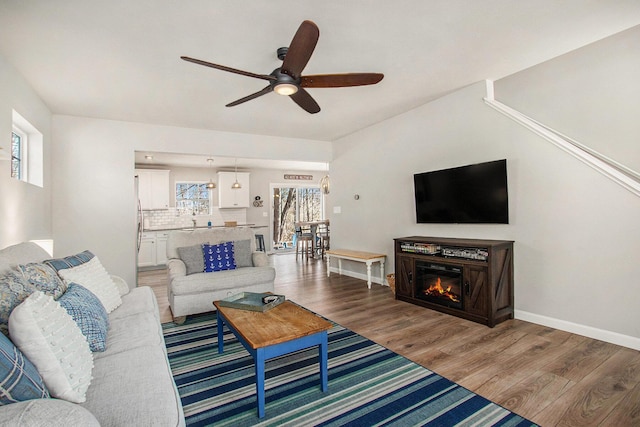 living room featuring a wealth of natural light, baseboards, ceiling fan, and wood finished floors