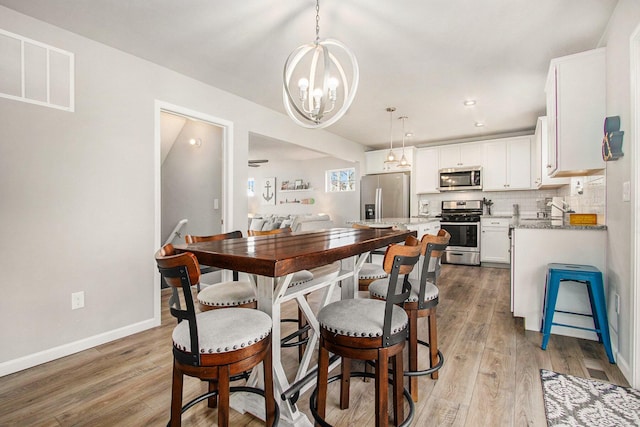 dining room featuring wood finished floors, baseboards, visible vents, recessed lighting, and a chandelier