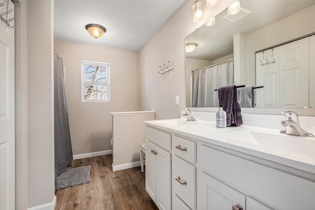 bathroom featuring double vanity, wood finished floors, toilet, and a sink