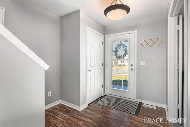 foyer entrance featuring visible vents, baseboards, and wood finished floors