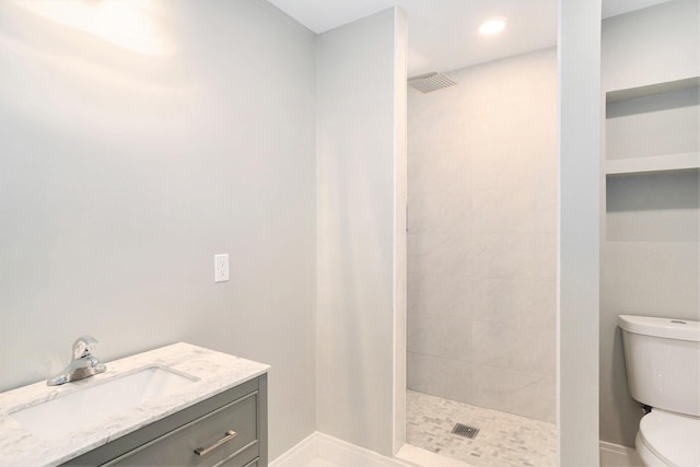 full bath with visible vents, toilet, vanity, and a tile shower