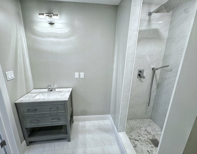 bathroom featuring baseboards, marble finish floor, vanity, and a tile shower