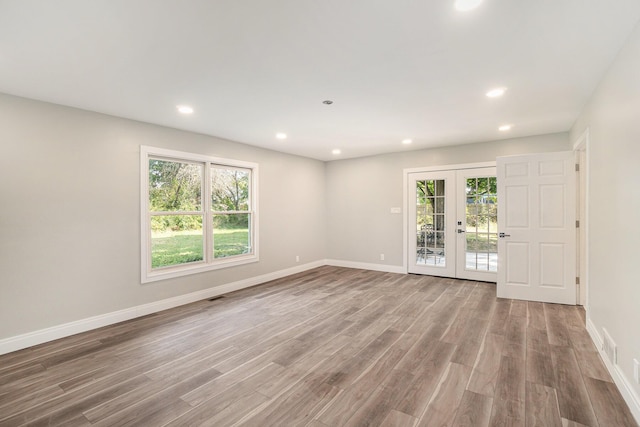 empty room with plenty of natural light, french doors, baseboards, and wood finished floors