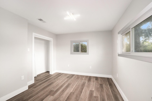 spare room with wood finished floors, visible vents, and baseboards