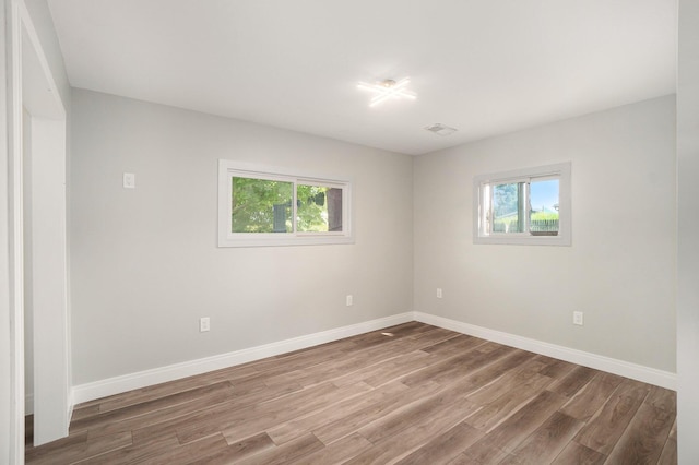 spare room with baseboards, plenty of natural light, and wood finished floors