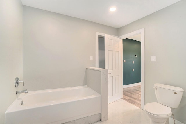 bathroom featuring a bathtub, toilet, and baseboards