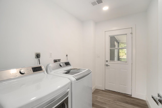 clothes washing area featuring visible vents, baseboards, laundry area, wood finished floors, and separate washer and dryer