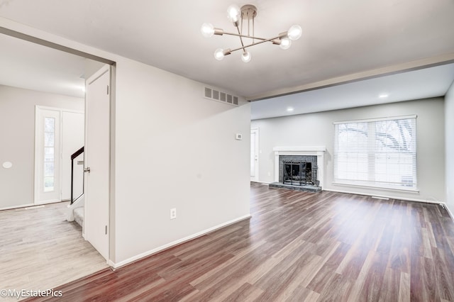 unfurnished living room featuring visible vents, wood finished floors, a fireplace, baseboards, and stairs