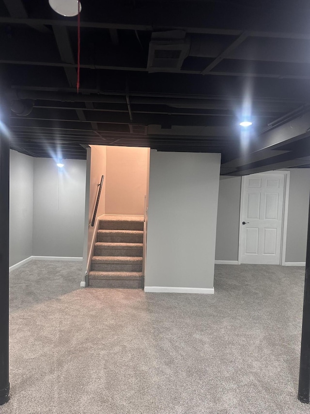 finished below grade area with stairway, baseboards, and carpet floors