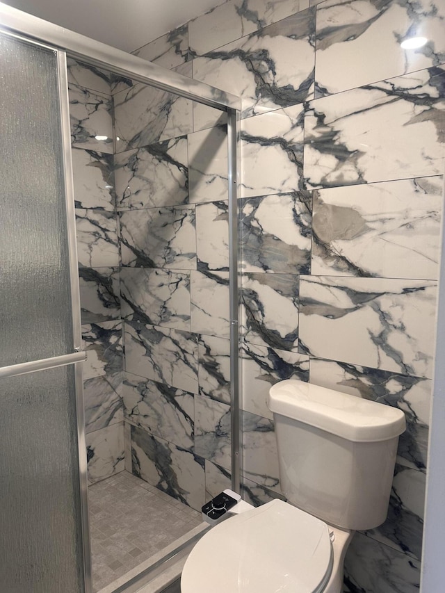 bathroom with a marble finish shower and toilet