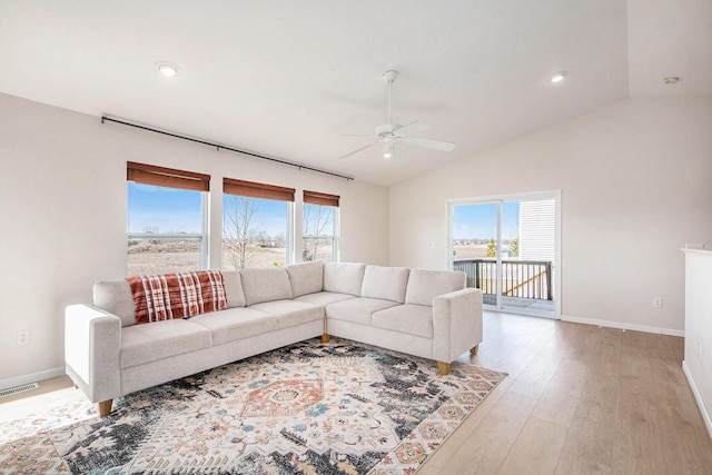 living area with a wealth of natural light, visible vents, light wood-style flooring, and vaulted ceiling