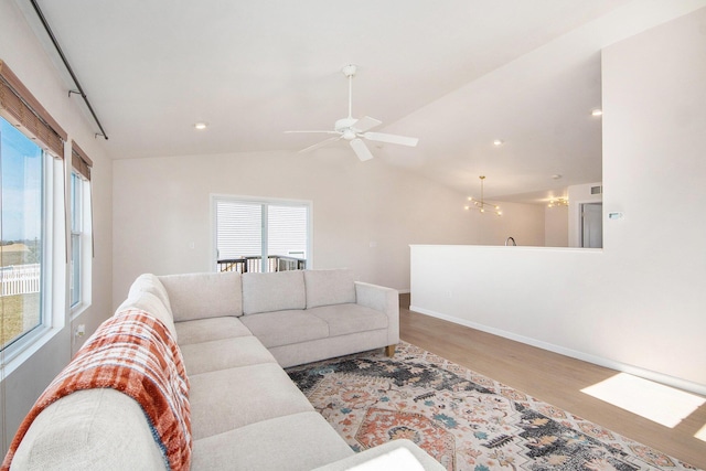 living area with wood finished floors, baseboards, recessed lighting, vaulted ceiling, and ceiling fan with notable chandelier