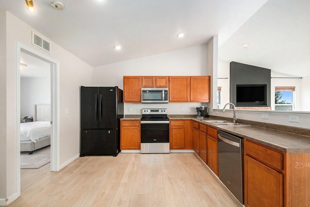 kitchen featuring visible vents, light wood-style flooring, a sink, stainless steel appliances, and brown cabinetry