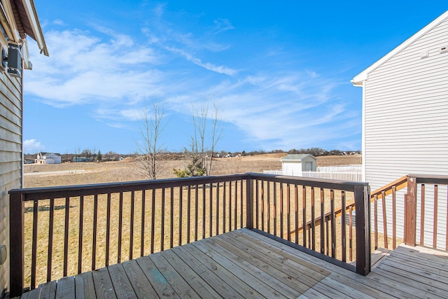 wooden terrace featuring a storage unit, an outbuilding, and a yard