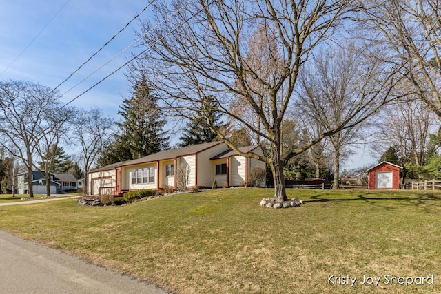 view of front of home featuring an outbuilding, a storage shed, a front yard, and fence