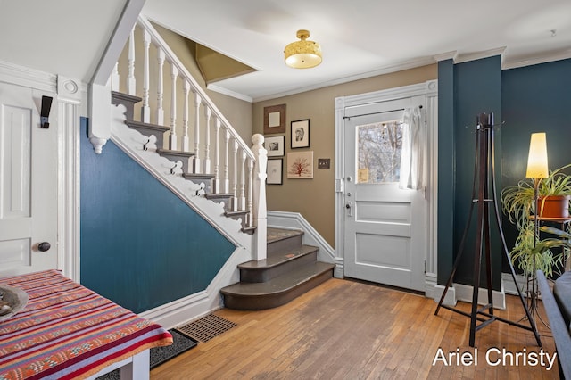 entrance foyer with stairs, visible vents, wood-type flooring, and crown molding