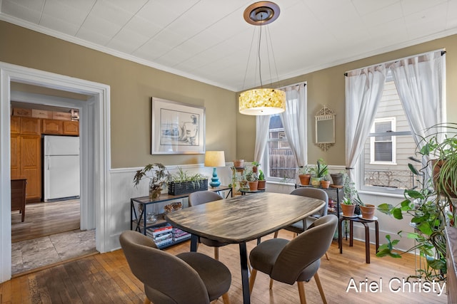 dining area with wainscoting, ornamental molding, and hardwood / wood-style flooring