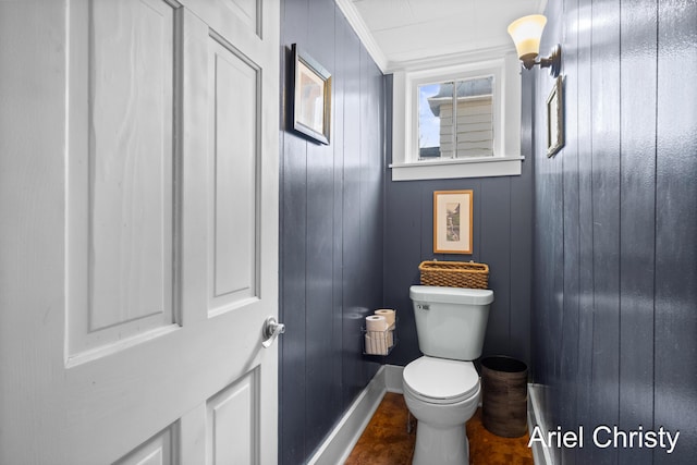 bathroom with baseboards, toilet, and crown molding