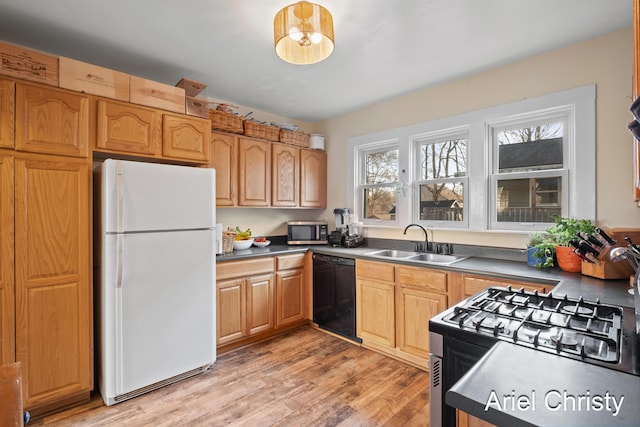 kitchen featuring stainless steel microwave, gas range, black dishwasher, freestanding refrigerator, and a sink