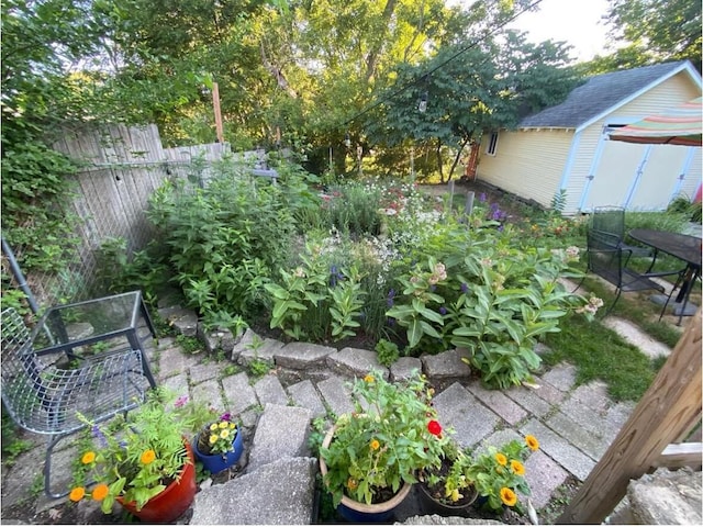 view of yard featuring a garden, an outdoor structure, and fence