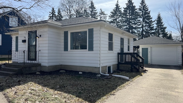 view of front of property with an outbuilding, concrete driveway, a garage, and a shingled roof