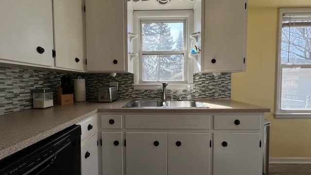 kitchen featuring a sink, tasteful backsplash, white cabinetry, light countertops, and dishwasher