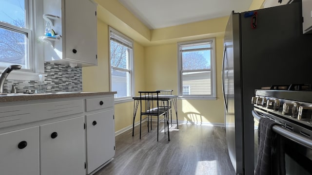 kitchen with tasteful backsplash, gas range, white cabinetry, and a wealth of natural light