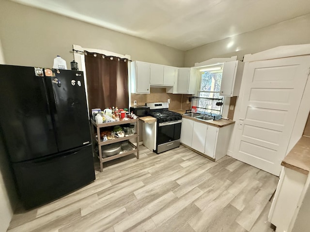 kitchen with a sink, black appliances, light countertops, light wood-style floors, and white cabinetry