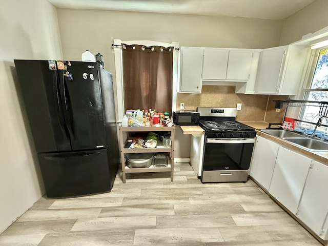 kitchen with tasteful backsplash, light wood-style flooring, white cabinets, black appliances, and a sink