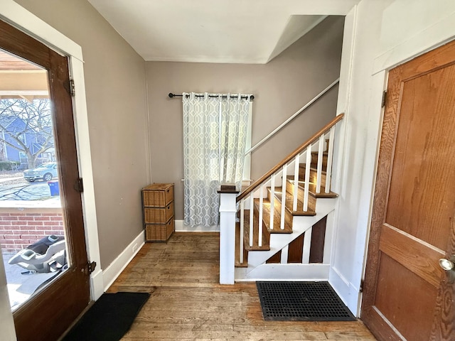 foyer entrance with baseboards, wood finished floors, and stairs