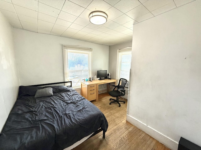 bedroom with baseboards, multiple windows, and light wood-style floors