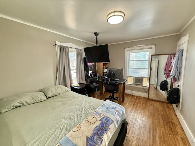 bedroom with crown molding, cooling unit, baseboards, and wood-type flooring