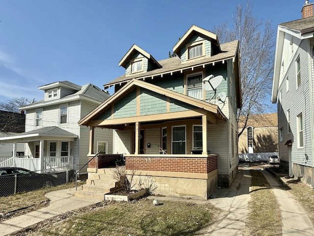 traditional style home featuring covered porch and fence