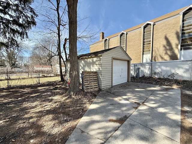 view of property exterior featuring a detached garage, fence, a chimney, an outbuilding, and driveway