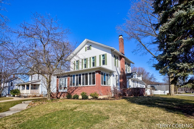 view of front of home featuring a front lawn, fence, brick siding, and a chimney