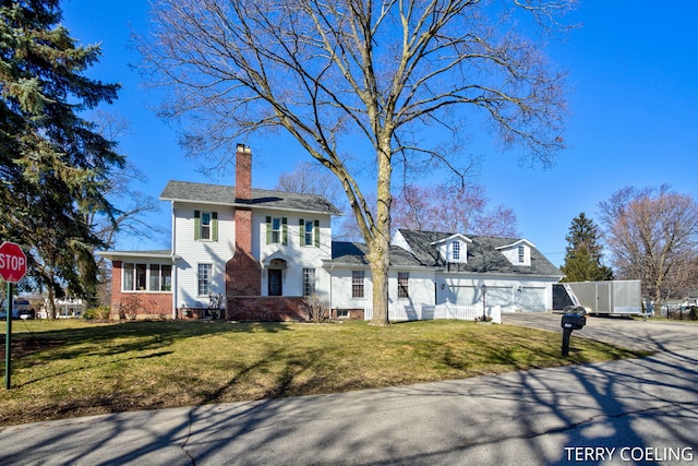 view of front of property with driveway, a chimney, a front lawn, and fence