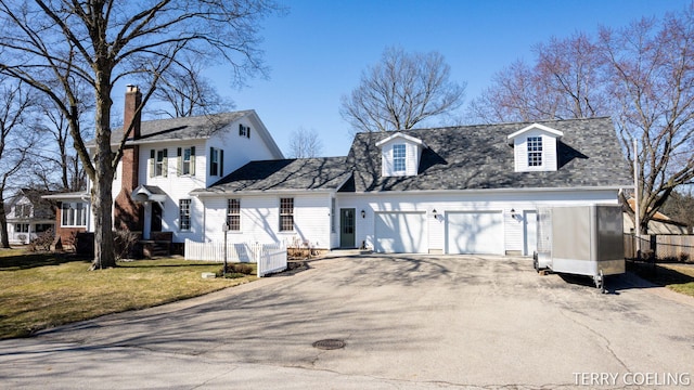 view of front facade with a front lawn, a chimney, a garage, and aphalt driveway