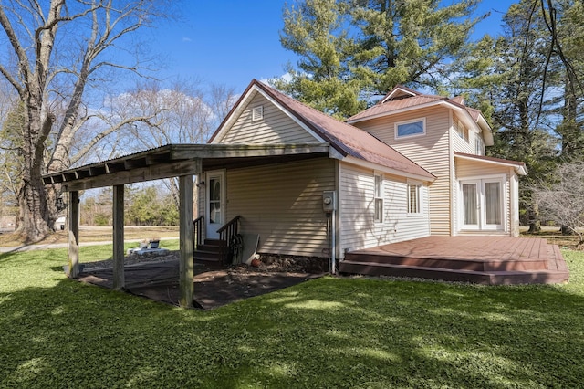 back of property featuring a lawn, a deck, entry steps, french doors, and an attached carport