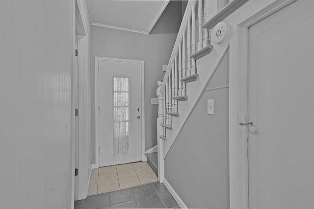 tiled entryway with a textured ceiling, ornamental molding, and stairs