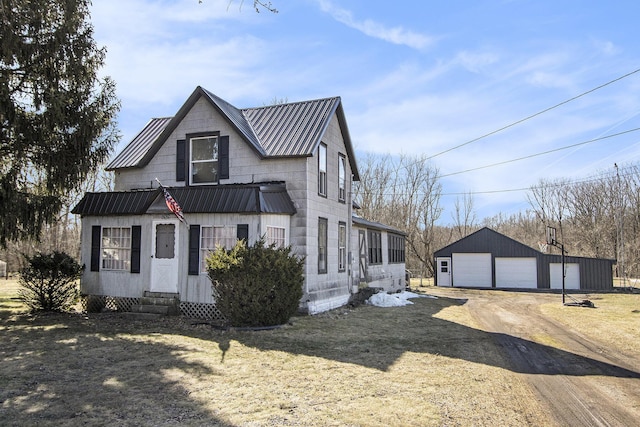 view of front facade with an outbuilding, entry steps, a detached garage, dirt driveway, and metal roof